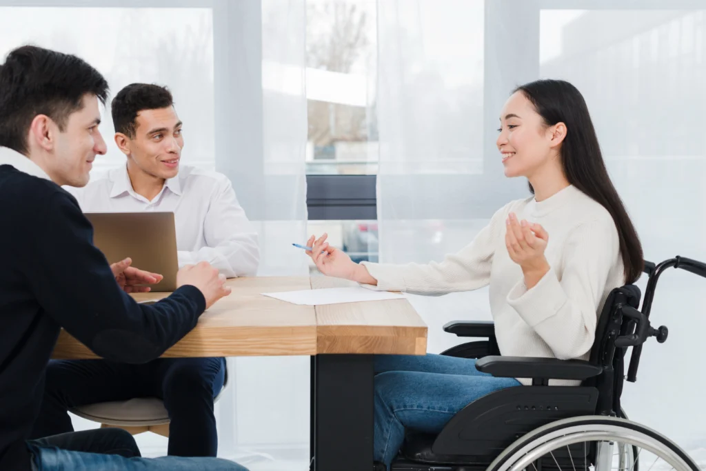 Cliente en silla de ruedas consultando opciones con agentes en una Agencia de Seguros en Mueller, Austin, TX