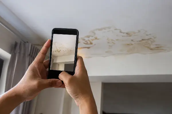 Dueño de casa documentando una mancha de agua en el techo tras una tubería rota
