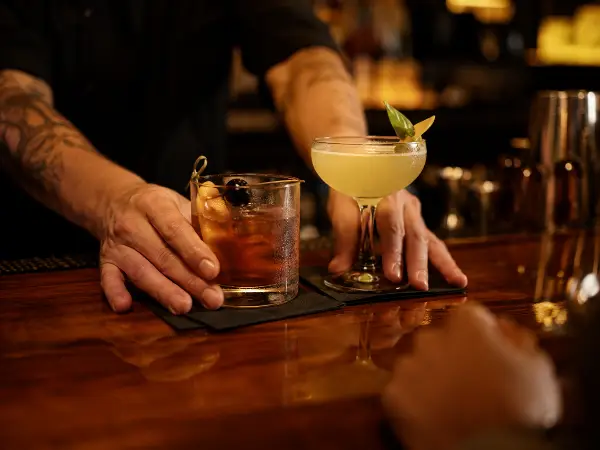 Cantinero sirviendo cocteles a un cliente en un bar de Austin